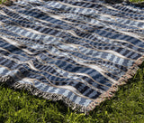 Sansevieria Leaf Cotton Throw Blanket in Blue, draped over a sofa