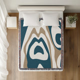 Shai Animal Print Cotton Throw Blanket in Teal and Beige, on a bed