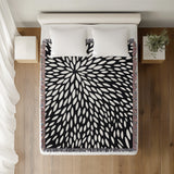 Addy Floral Cotton Throw Blanket in Black, on a bed