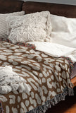Delo Animal Print Cotton Blend Blanket Throw in Rust Brown, draped over a chair