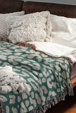 Delo Animal Print Cotton Blend Blanket Throw in Teal, draped over a chair