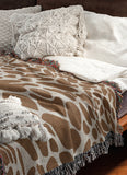 Zuma Animal Print Cotton Blend Blanket Throw in Rust Brown, draped over a chair