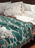 Zuma Animal Print Cotton Blend Blanket Throw in Teal, draped over a chair