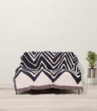Addai Abstract Triangle Pattern Blanket Throw in Black and Beige, draped over a sofa