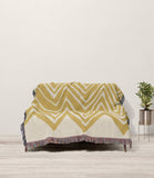 Addai Abstract Triangle Pattern Blanket Throw in Gold and Beige, draped over a sofa