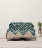 Addai Abstract Triangle Pattern Blanket Throw in Teal and Beige, draped over a sofa