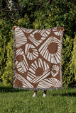 Kio Abstract Print Cotton Throw Blanket in Rust Brown, outdoors