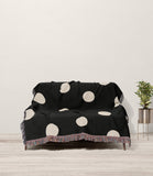 Akon Hand Woven Throw Blanket in Black and Beige, draped over a sofa