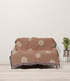 Akon Hand Woven Throw Blanket in Rust and Beige, draped over a sofa