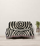Alaka Circles Cotton Throw Blanket in Black and Beige, draped over a sofa