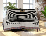 Bauhaus Eye Abstract Cotton Blend Blanket Throw in Beige, Black and Off-White, draped over a chair
