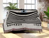 Bauhaus Eye Abstract Cotton Blend Blanket Throw in Blue, Black and Off-White, draped over a chair