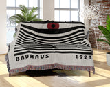 Bauhaus Eye Abstract Cotton Blend Blanket Throw in Red, Black and Off-White, draped over a chair