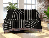 Askii Cotton Blend Blanket Throw in Black, draped over a chair