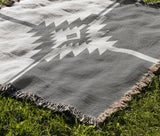 Asko Southwestern Cotton Blend Blanket Throw in Gray and Off-White, draped over a chair
