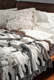 Bolt Leopard Cotton Blend Blanket Throw in Black and Off-White, draped over a chair