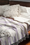 Bolt Leopard Cotton Blend Blanket Throw in Lilac and Off-White, draped over a chair
