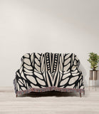 Buga Abstract Print Cotton Throw Blanket in Black and Beige, draped over a sofa