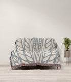 Buga Abstract Print Cotton Throw Blanket in Gray and Beige, draped over a sofa