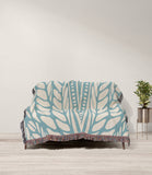 Buga Abstract Print Cotton Throw Blanket in Sky Blue and Beige, draped over a sofa