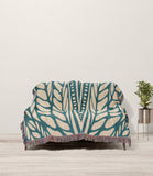 Buga Abstract Print Cotton Throw Blanket in Teal and Beige, draped over a sofa