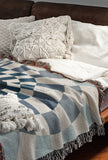 Bullseye Abstract Cotton Blend Blanket Throw in Blue and Off-White, draped over a chair