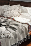 Bullseye Abstract Cotton Blend Blanket Throw in Gray and Off-White, draped over a chair