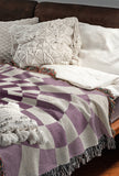 Bullseye Abstract Cotton Blend Blanket Throw in Purple and Off-White, draped over a chair