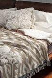 Chitto Southwestern Cotton Blend Blanket Throw in Beige and Off-White, draped over a chair