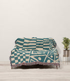 Cocodili Abstract Print Cotton Throw Blanket in Teal and Beige, draped over a sofa