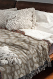 Delo Animal Print Cotton Blend Blanket Throw in Beige, draped over a chair