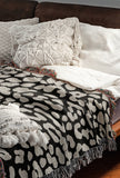 Delo Animal Print Cotton Blend Blanket Throw in Black, draped over a chair