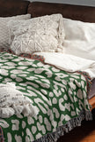 Delo Animal Print Cotton Blend Blanket Throw in Green, draped over a chair