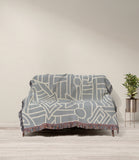 Diof Abstract Print Cotton Throw Blanket in Gray and Beige, draped over a sofa