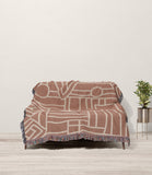 Diof Abstract Print Cotton Throw Blanket in Beige and Rust, draped over a sofa