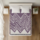 Addai Abstract Triangle Pattern Blanket Throw in Purple, on a bed