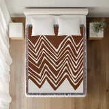 Addai Abstract Triangle Pattern Blanket Throw in Rust Brown, on a bed