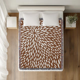 Addy Floral Cotton Throw Blanket in Rust Brown, on a bed