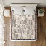Afia Tribal Cotton Throw Blanket in Beige, on a bed
