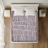 Afia Tribal Cotton Throw Blanket in Purple, on a bed