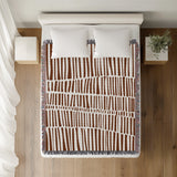 Afia Tribal Cotton Throw Blanket in Rust Brown, on a bed