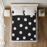 Akon Hand Woven Throw Blanket in Black, on a bed