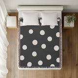 Akon Hand Woven Throw Blanket in Gray, on a bed