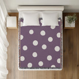 Akon Hand Woven Throw Blanket in Purple, on a bed