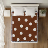 Akon Hand Woven Throw Blanket in Rust Brown, on a bed