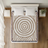 Alaka Circles Cotton Throw Blanket in Beige, on a bed