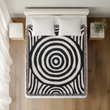 Alaka Circles Cotton Throw Blanket in Black, on a bed