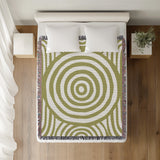 Alaka Circles Cotton Throw Blanket in Chartreuse, on a bed
