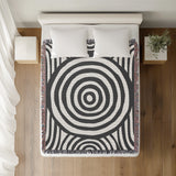 Alaka Circles Cotton Throw Blanket in Gray, on a bed