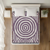 Alaka Circles Cotton Throw Blanket in Purple, on a bed